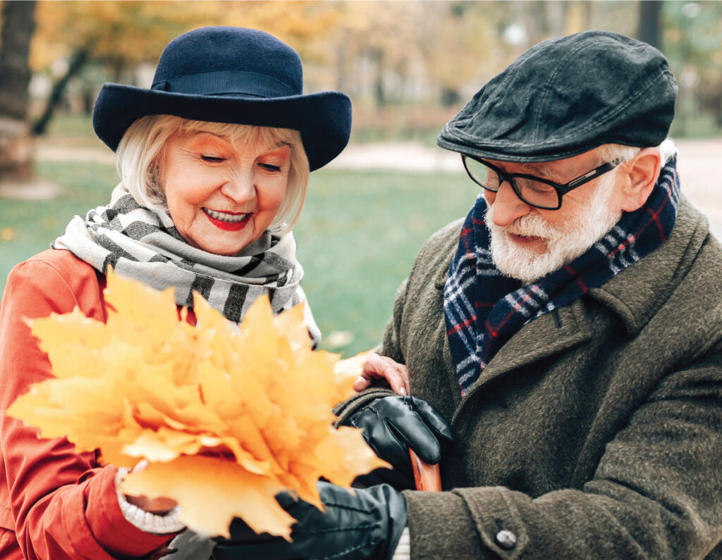 Senior woman holding a bouquet of leaves with her male friend wearing glasses