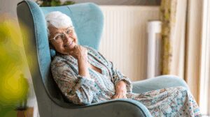 Senior female Assisted Living resident smiling and reclining in a blue chair